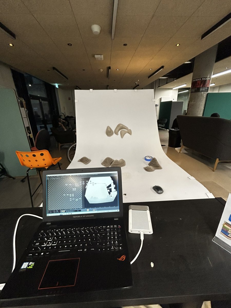 A self-built photogrammetry rig — laptop running scanning software beside a turntable backdrop for capturing the topographic models