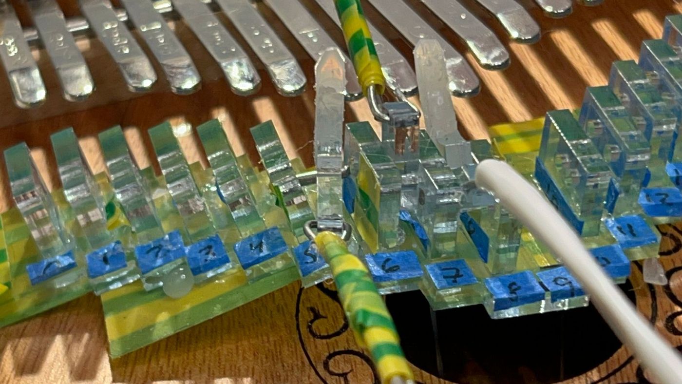 Close-up of clear laser-cut acrylic tines mounted in a row
