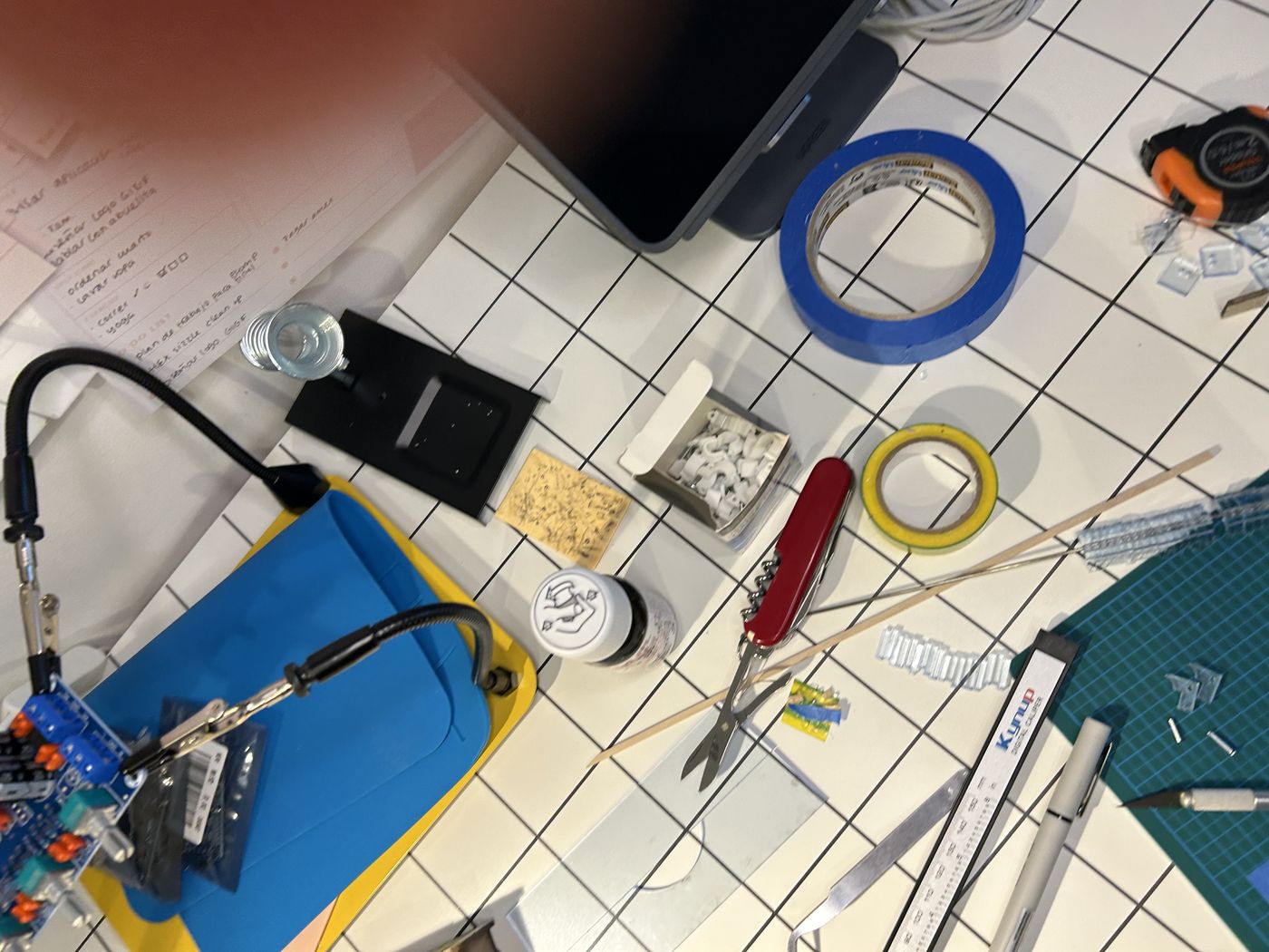 Top-down view of the desk — cutting mat, tape, pliers and electronics